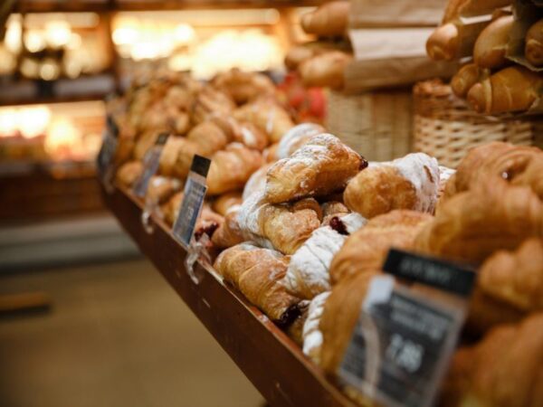 A wide bakery display shelf filled with freshly baked powdered pastries, croissants, and artisan breads at Le Rouge Bakery.