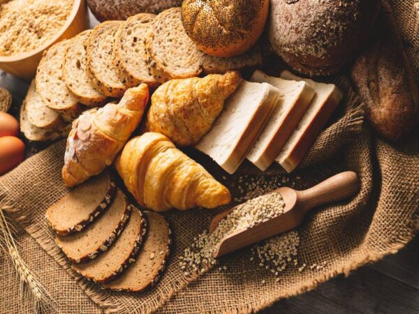 An assortment of fresh bakery goods, sliced whole-grain breads, and croissants.