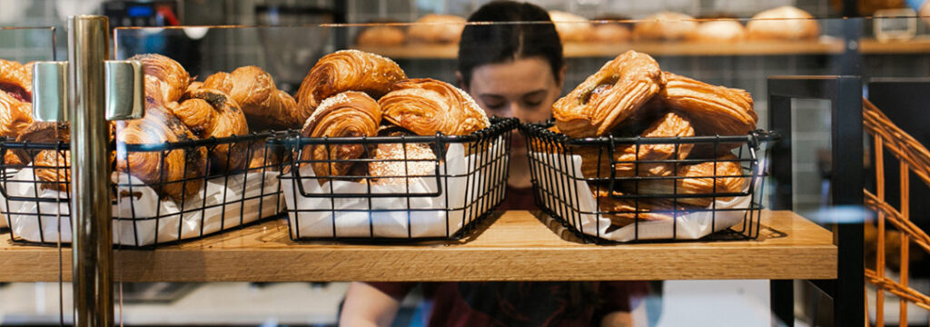 Assortment of golden, flaky artisan pastries on the bakery display shelf at LeRouge Boulangerie.