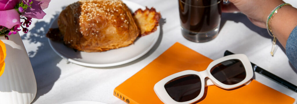 A customer enjoying an iced coffee and pastries while working on an orange notebook, as featured on the LeRouge Bakery blog.